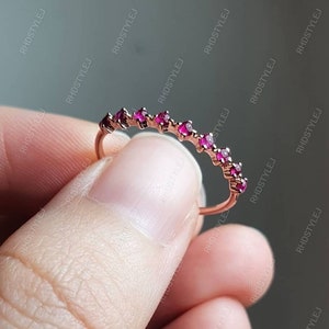 May include: A delicate rose gold band ring with a row of small, sparkling pink gemstones.