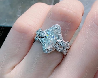 May include: A silver engagement ring featuring a large marquise-shaped diamond surrounded by smaller diamonds. The ring has a delicate floral design.