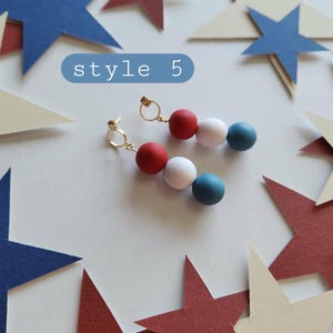 May include: A pair of drop earrings featuring three spherical beads in red, white, and blue, suspended from gold-toned circular hoops. The text style 5 is visible in a blue rounded rectangle above the earrings, which are surrounded by paper stars.