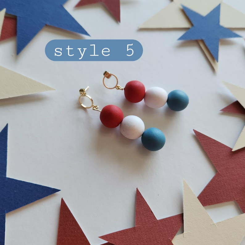 May include: A pair of drop earrings featuring three spherical beads in red, white, and blue, suspended from gold-toned circular hoops. The text style 5 is visible in a blue rounded rectangle above the earrings, which are surrounded by paper stars.