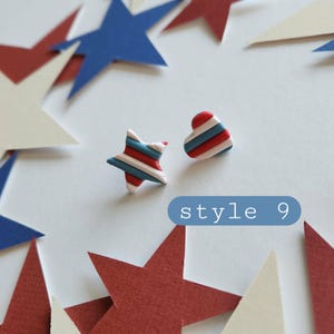 May include: A pair of stud earrings featuring one star-shaped piece and one heart-shaped piece, both decorated with horizontal red, white, and blue stripes. A blue rectangular label with white text reads style 9.