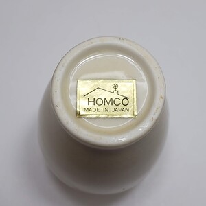 K&ouml;nnte beinhalten: Wei&szlig;e Keramiktasse mit einem goldenen Etikett mit der Aufschrift "HOMCO MADE IN JAPAN".