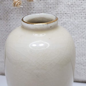 K&ouml;nnte beinhalten: Eine kleine, wei&szlig;e Keramikvase mit goldfarbenem Rand. Die Vase hat eine strukturierte Oberfl&auml;che und ist perfekt f&uuml;r die Pr&auml;sentation einer einzelnen Blume.