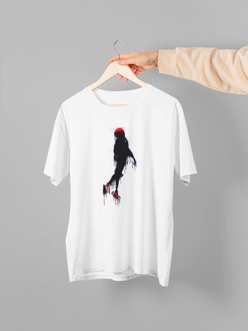 May include: White t-shirt with a graphic of a person in a red hat jumping, painted in a watercolor style with black, red, blue, and purple colors.
