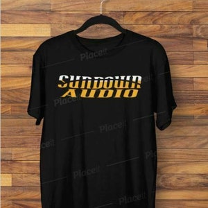 Könnte beinhalten: Schwarzes T-Shirt mit dem Text "Sundown Audio" in gelben und weißen Buchstaben.