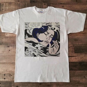 May include: White t-shirt with a graphic print of a woman crying in a blue and black wave. The text in the speech bubble reads "I don't care if I rather sink than call Brad for help!"
