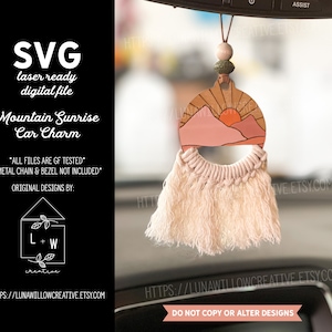 May include: A pink and orange mountain sunrise car charm with a macrame tassel hanging from a rearview mirror. The charm is made of wood and has a laser-cut design. The text "Mountain Sunrise Car Charm" is visible in the image.