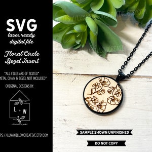 May include: A laser-cut wooden circle with a floral design, ready to be used as a bezel insert for jewelry making. The circle is shown on a black chain necklace, but the chain and bezel are not included. The image includes the text "Floral Circle Bezel Insert" and "All files are GF tested".