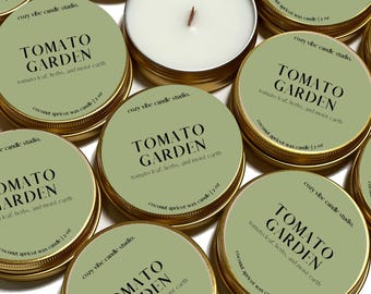 May include: A collection of small, round candles in gold tins. Each candle has a light green label with the words "TOMATO GARDEN" in black, along with text about the scent. The candles are coconut apricot wax, 2 oz.