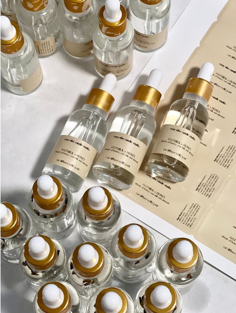 May include: A collection of small glass bottles with gold lids and labels. The labels are white with black text that reads "Oatmilk + Honey" and "car diffuser oil 15ml".