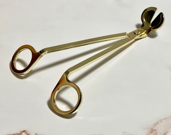 May include: Gold candle wick trimmer with a pair of round handles and a small, round, double-pronged head for trimming wicks.