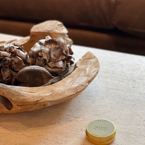 May include: A gold metal container with a black label that reads "SPA DAY soy wax candle 1.7 oz".