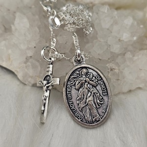 May include: Silver chain necklace with two charms: a silver crucifix and a silver oval charm with the image of Our Lady, Undoer of Knots. The oval charm has the text "Our Lady Undoer of Knots" around the edge.