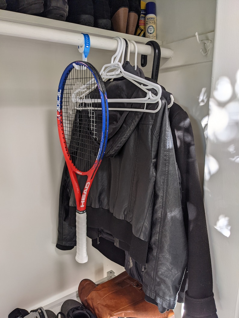 Puede incluir: Una raqueta de tenis roja, blanca y azul colgada de un gancho en un armario. La raqueta es de la marca Head y tiene el texto "Graphene 360+ Speed MP".