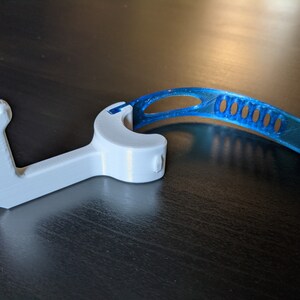 Puede incluir: Un gancho de pl&aacute;stico blanco con una correa de pl&aacute;stico azul. El gancho est&aacute; dise&ntilde;ado para ayudar a abrir puertas y otras superficies sin tocarlas.