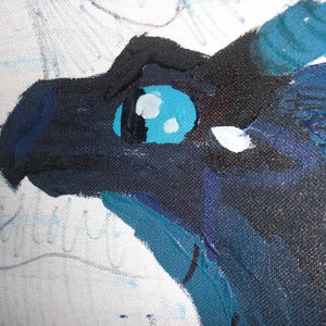May include: Close-up of a painting of a dragon's head. The dragon is painted with shades of blue and black, with a bright blue eye and white highlights. The artwork is on a canvas.