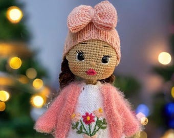 Puede incluir: Muñeca de ganchillo hecha a mano con un gorro rosa con lazo y rebeca a juego. La muñeca tiene una cara de ganchillo con ojos oscuros y labios rojos. El vestido blanco presenta un diseño floral bordado. Un artículo encantador, hecho a mano.