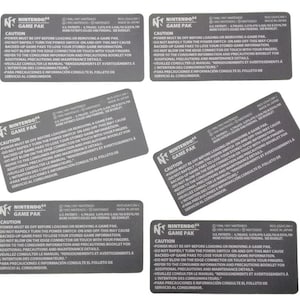 May include: A collection of six gray Nintendo 64 Game Pak cartridges. Each cartridge features the Nintendo logo and warning text in multiple languages, including English, French, and Spanish.