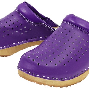 May include: A pair of purple leather clogs with a wooden sole and a perforated design. The clogs have a white stitching detail around the edges.