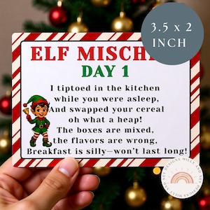 Puede incluir: Tarjeta rectangular con bordes a rayas rojas y blancas y el texto "ELF MISCHIEF DAY 1". La tarjeta presenta un duende de dibujos animados y el texto "3.5 x 2 INCH". La tarjeta está sujeta por una mano.