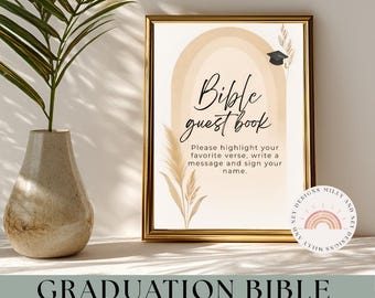 May include: A framed sign with the text "Bible guest book" in elegant script. The sign features a graduation cap illustration and instructions to highlight a favorite verse and sign a name. The frame is gold, and the background is beige.