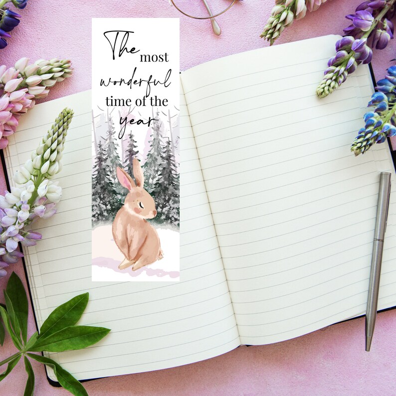 May include: A bookmark featuring a watercolor illustration of a brown rabbit sitting in a snowy forest. The text "The most wonderful time of the year" is printed at the top of the bookmark.