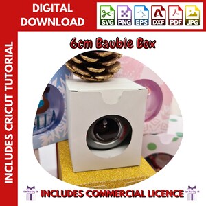 May include: A white cardboard box with a cut-out window to display a 6 cm bauble. The box is decorated with a gold glitter border. The image includes the text "6cm Bauble Box" and "INCLUDES COMMERCIAL LICENCE".