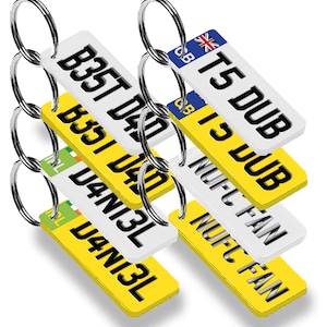 May include: A set of six keychains with different designs. Each keychain features a white rectangular tag with black text and a yellow background. The tags have different text, including "Best Dad", "T5 DUB", "I3 DUB", "NUFC FAN", and "D4N13L".