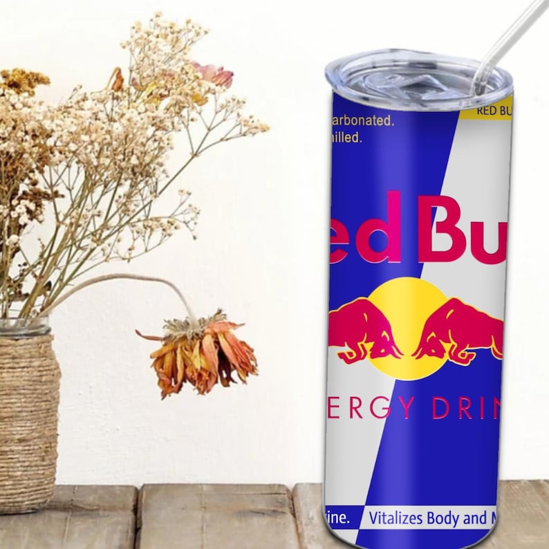 May include: A stainless steel tumbler with a red bull energy drink design. The tumbler has a blue and white background with the red bull logo and the text "Red Bull Energy Drink" and "Vitalizes Body and Mind".