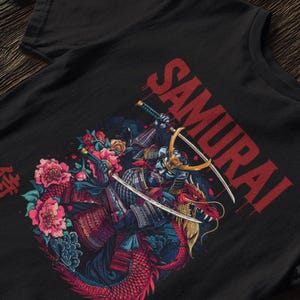 May include: Black t-shirt featuring a detailed illustration of a samurai warrior riding a dragon, with swords and floral elements. The word "SAMURAI" is printed in red across the top.