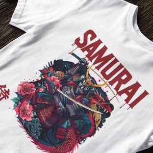 May include: White t-shirt featuring a detailed graphic of a samurai warrior riding a dragon, with the word "SAMURAI" in red. The design includes floral elements and Japanese text.