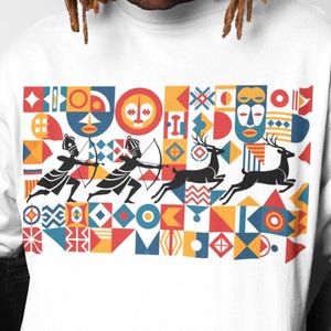 Peut inclure: T-shirt blanc à manches longues avec un motif géométrique coloré. Le motif comprend des archers, des cerfs et des masques tribaux en rouge, jaune, bleu et noir. Le t-shirt est en matière souple.