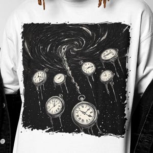 Op de afbeelding: Wit shirt met lange mouwen met een zwart-witte afbeelding van zakhorloges in een wervelende vortex. De horloges hebben een klassiek ontwerp met Romeinse cijfers. Het shirt heeft een ronde hals en is gemaakt van een zacht materiaal.