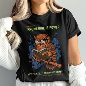 Owl wearing glasses reads a book on a branch, "Knowledge is Power."