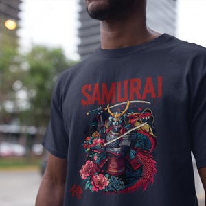 May include: Navy blue t-shirt featuring a graphic of a samurai warrior with a dragon, swords, and flowers. The word "SAMURAI" is printed in red above the illustration. The Japanese kanji character for "wait" is printed below.