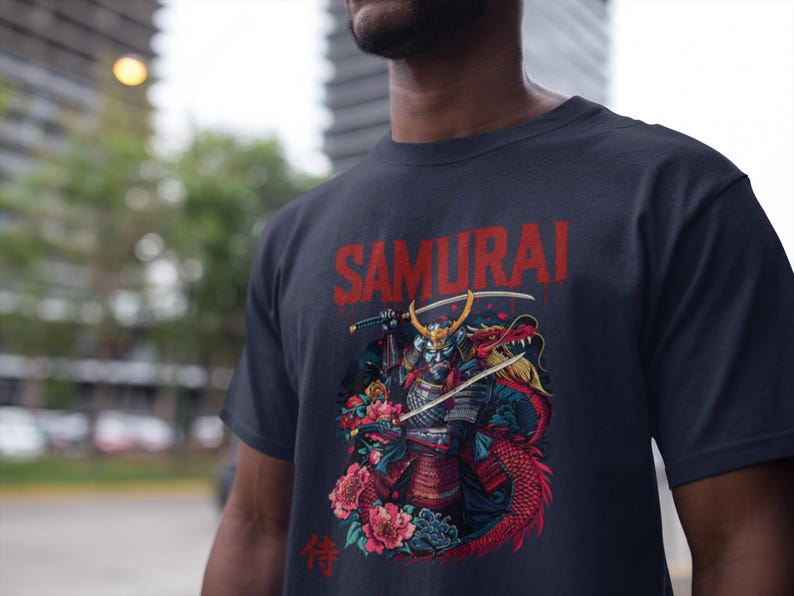 May include: Navy blue t-shirt featuring a graphic of a samurai warrior with a dragon, swords, and flowers. The word "SAMURAI" is printed in red above the illustration. The Japanese kanji character for "wait" is printed below.