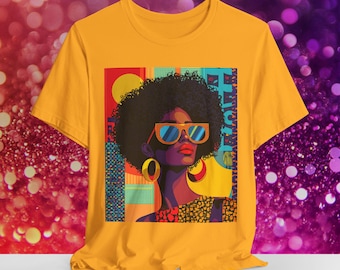 May include: A yellow t-shirt with a colorful graphic print of a woman with sunglasses and a large hoop earring. The text "Black Girl Magic" is printed on the shirt.