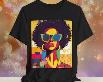May include: A black t-shirt with a colorful graphic print of a woman with an afro wearing sunglasses. The background is a mix of geometric shapes in bright colors.