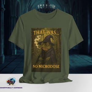 Peut inclure: Un t-shirt vert avec une image de dessin animé d'une grenouille portant un chapeau de sorcier et fumant une pipe. Le texte "That was... No microdose" est imprimé sur le t-shirt.