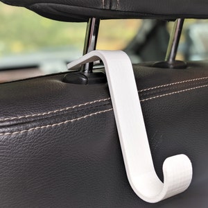 May include: White plastic hook designed to hang items from the headrest of a car seat.