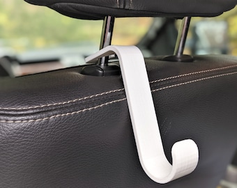 May include: White plastic hook designed to hang items from the headrest of a car seat.