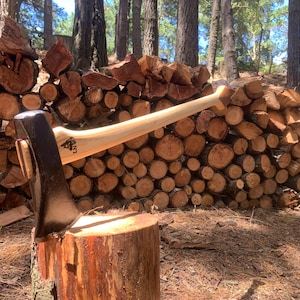 May include: Axe with a wooden handle and a dark metal head, resting on a tree stump. The axe is positioned in front of a stack of firewood, with a forest backdrop. The axe is a tool for chopping wood.