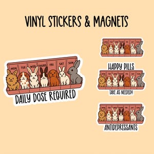 May include: Vinyl stickers and magnets with cartoon rabbits and dogs in a pill organiser design. The stickers have text that reads "Daily Dose Required", "Happy Pills, Take as Needed!!", and "Antidepressants". The stickers are on a light orange background.