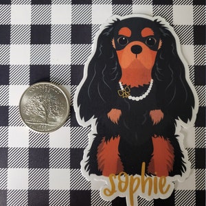 May include: A black and brown Cavalier King Charles Spaniel dog sticker with the name "Sophie" written in gold lettering.
