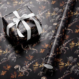 May include: Black wrapping paper with a dinosaur and foliage pattern. A wrapped gift box with a white ribbon sits on the paper, next to a roll of the same paper. The dinosaurs are in shades of brown and gray, with orange and gray foliage.
