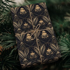 Puede incluir: Papel de regalo negro y dorado con un patr&oacute;n repetido de dise&ntilde;os florales estilizados. El papel de regalo est&aacute; atado con un lazo de cuerda marr&oacute;n.