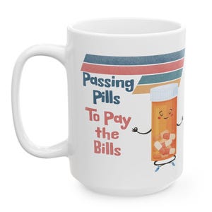 May include: White ceramic mug with a retro-style design featuring a cartoon pill bottle with a smiling face and the text "Passing Pills To Pay the Bills".