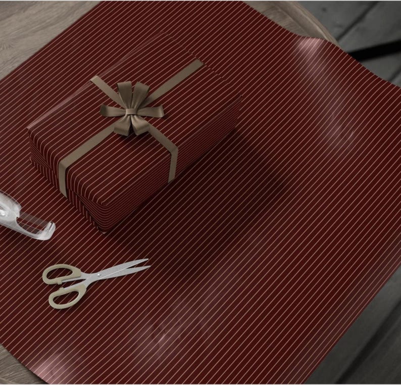 Op de afbeelding: Rood en goud gestreept cadeaupapier met een gouden lint en strik op een cadeaudoos.