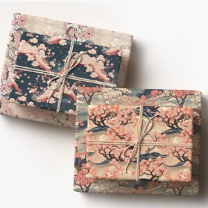 May include: Two wrapped gifts with Japanese-inspired floral patterns. The top gift is wrapped in a navy blue paper with pink cherry blossoms, tied with twine. The bottom gift has a peach-colored paper with a similar design.