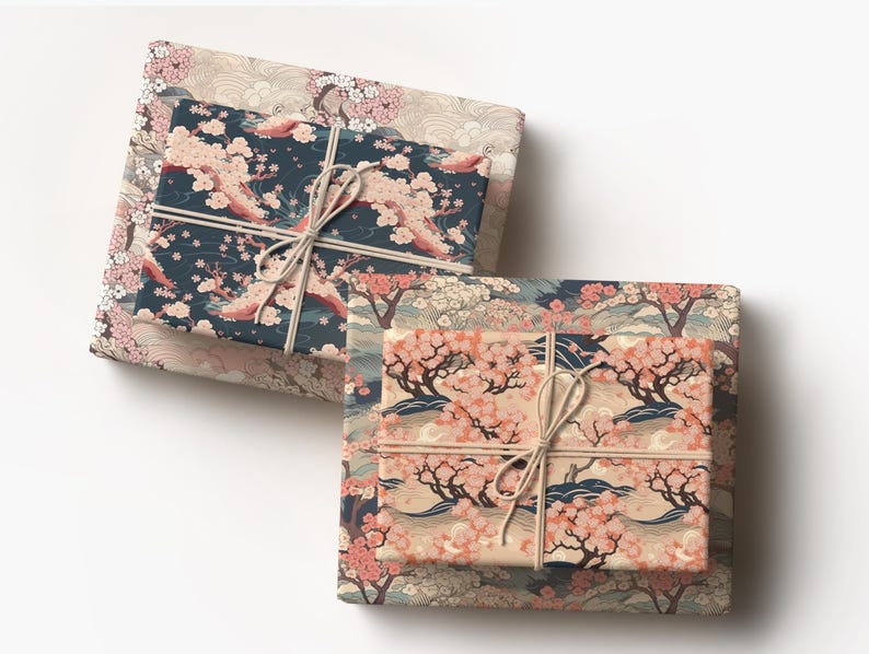 May include: Two wrapped gifts with Japanese-inspired floral patterns. The top gift is wrapped in a navy blue paper with pink cherry blossoms, tied with twine. The bottom gift has a peach-colored paper with a similar design.